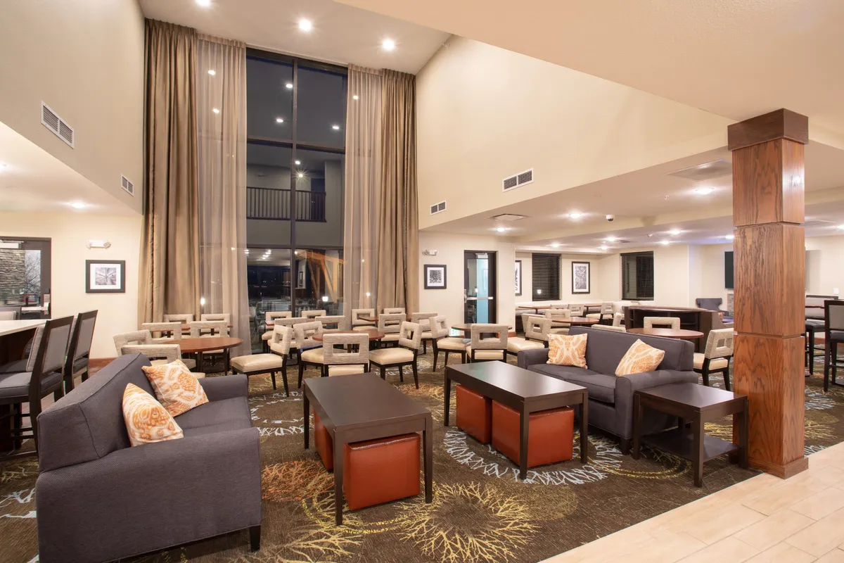 A well-lit living area with large windows, comfortable seating, stylish tables, and decorative pillows. The room exudes a homely vibe, making it perfect for relaxation, reading, or catching up on work in a bright, inviting space.